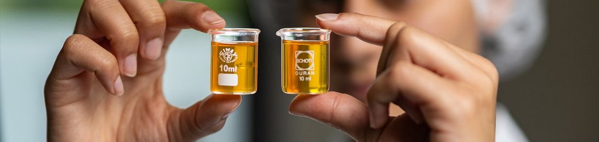 Detailaufnahme von zwei Laborgefäßen mit Substanz in den Händen von Mitarbeitenden