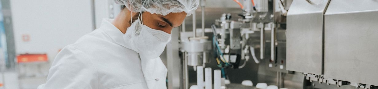Arbeit an einer Produktionsanlage in hygienischer Umgebung mit Schutzkleidung und Maschinen